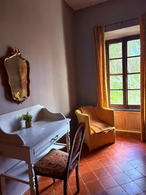 a room with a table and a chair and a window at O'MAZETTE CHAMBRE ROMANTIQUE VUE JARDIN AVEC PISCINE découverte de l'Aude in Fabrezan