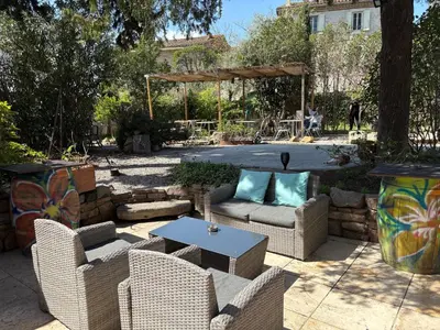 a patio with wicker chairs and a table with a table at O'MAZETTE CHAMBRE ROMANTIQUE VUE JARDIN AVEC PISCINE découverte de l'Aude in Fabrezan