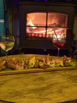 a plate of food and two glasses of wine at O'MAZETTE CHAMBRE ROMANTIQUE VUE JARDIN AVEC PISCINE découverte de l'Aude in Fabrezan