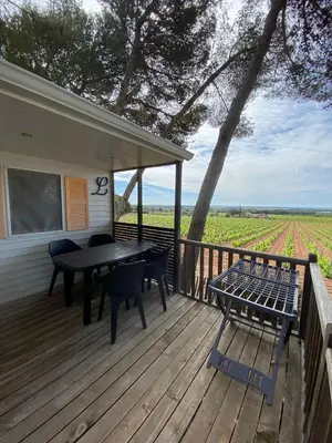 a wooden deck with a table and chairs on it at Camping Le Bois De Pins in Salses-le-Chateau