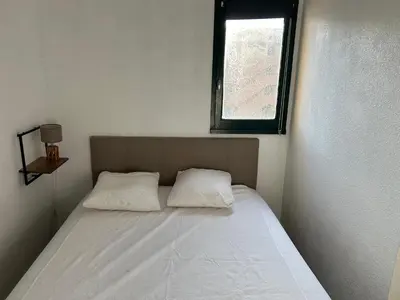 a bed with two pillows in a room with a window at Appart Gwen in Gruissan