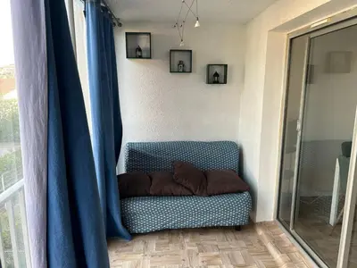 a blue couch sitting in a room with a window at Appart Gwen in Gruissan