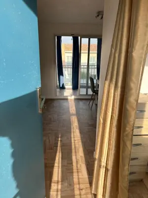 a room with a hallway with a wooden floor and curtains at Appart Gwen in Gruissan