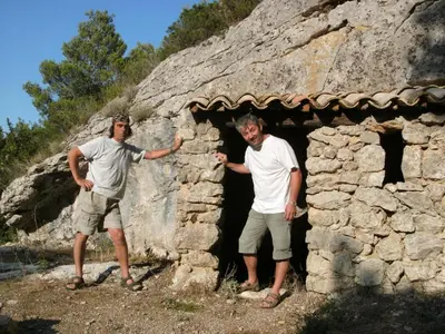 two men standing in front of a stone building at Maison tout confort belle terrasse sud in Sigean