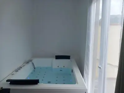 a bath tub in a white room with a window at White and Cotton Suite in Saint-Paul-de-Fenouillet