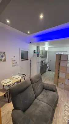 a living room with a couch and a kitchen at Le petit cocon centre ville in Tuchan