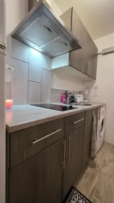 a kitchen with wooden cabinets and a stove top oven at Le petit cocon centre ville in Tuchan