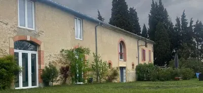 a large brick house with trees in the background at Dortoir de 12Lits in Mas-Saintes-Puelles