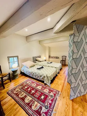 a bedroom with two beds and a rug at Le Moulin de La Grave 450m2 in Lagrasse