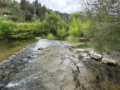 a stream of water with rocks and trees at Le Moulin de La Grave 450m2 in Lagrasse