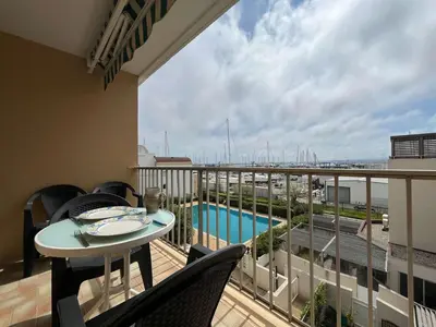 a balcony with a table and a view of a pool at Appartement climatisé, vue sur le port technique - GN160-331 in Gruissan