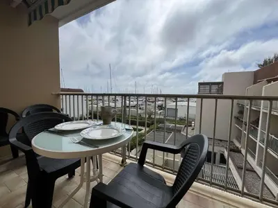 a balcony with a table and chairs and a view of the ocean at Appartement climatisé, vue sur le port technique - GN160-331 in Gruissan