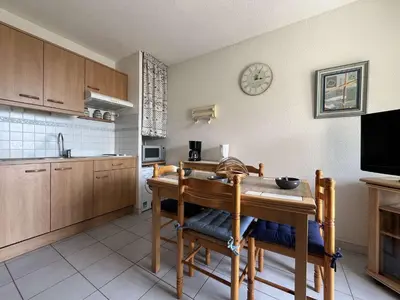 a kitchen with a table and a clock on the wall at Appartement climatisé, vue sur le port technique - GN160-331 in Gruissan