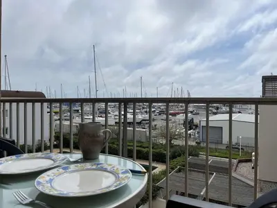 a table with plates on a balcony with a view of a harbor at Appartement climatisé, vue sur le port technique - GN160-331 in Gruissan