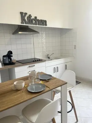a kitchen with a wooden table and white chairs at Aux 138 bis in Carcassonne