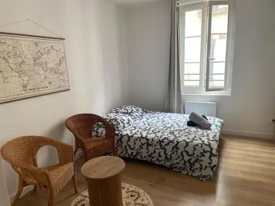a bedroom with a bed and two chairs and a window at Le Mi-Stud in Castres