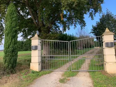 a gate in a field with a tree at Roulotte et Nature in Mirepoix