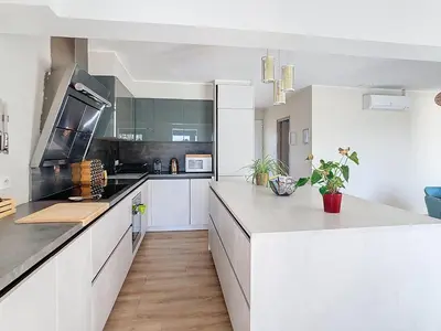 a kitchen with white cabinets and a large counter at La terrasse du Canal, appartement pour 5 personnes in La Redorte