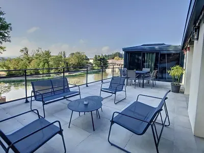 a patio with chairs and tables and a view of the water at La terrasse du Canal, appartement pour 5 personnes in La Redorte