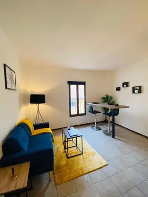 a living room with a blue couch and a table at Logement coeur de ville in Narbonne