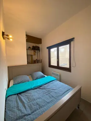 a bedroom with a bed with blue sheets and a window at Logement coeur de ville in Narbonne