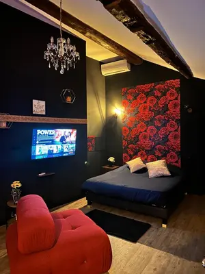 a bedroom with a bed and a chair and a tv at Love room Narbonnaise in Narbonne