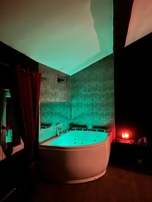 a large bath tub in a bathroom with green tile at Love room Narbonnaise in Narbonne
