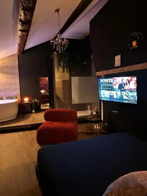 a living room with a tv and two ottomans at Love room Narbonnaise in Narbonne