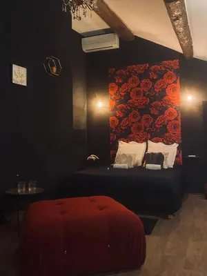 a bedroom with a bed with a red floral wall at Love room Narbonnaise in Narbonne