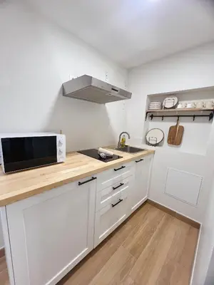 a kitchen with white cabinets and a microwave at Japandi en centre-ville in Narbonne