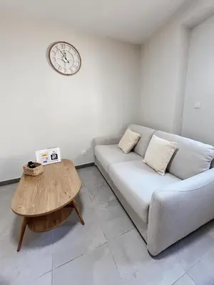 a living room with a couch and a clock on the wall at Japandi en centre-ville in Narbonne