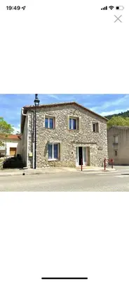 a stone building with blue windows on a street at La forge in Laroque-de-Fa