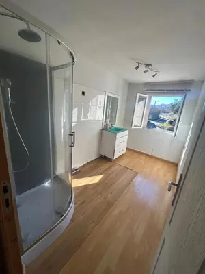 a bathroom with a glass shower and a wooden floor at La forge in Laroque-de-Fa