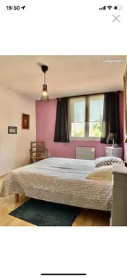 a bedroom with a large bed and a pink wall at La forge in Laroque-de-Fa