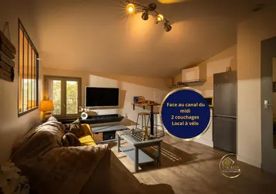 a living room with a couch and a tv at Le refuge du canal Local à vélo Face canal du midi in Castelnaudary
