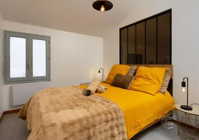 a bedroom with a large bed with a yellow blanket at Le refuge du canal Local à vélo Face canal du midi in Castelnaudary