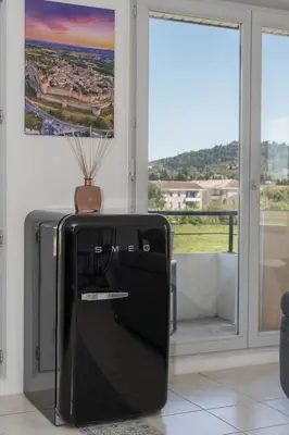 a black suitcase sitting in a room with a window at Lumaïa - Vue cité, terrasse & Piscine in Carcassonne