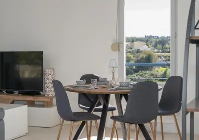a dining room table with chairs and a television at Lumaïa - Vue cité, terrasse & Piscine in Carcassonne