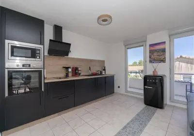 a kitchen with black cabinets and a microwave at Lumaïa - Vue cité, terrasse & Piscine in Carcassonne