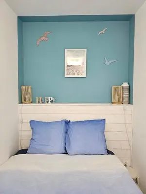 a bedroom with a blue wall and a bed with blue pillows at Studio cabine climatisé magnifique vue port in Gruissan