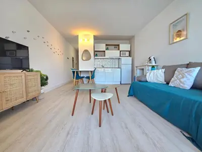 a living room with a blue couch and a table at Studio cabine climatisé magnifique vue port in Gruissan
