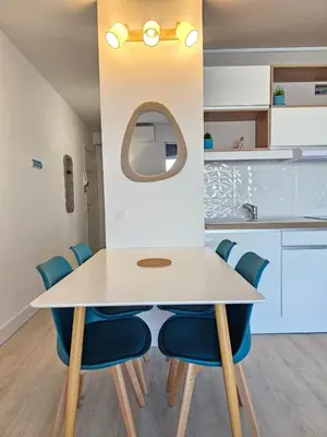 a dining room with a white table and blue chairs at Studio cabine climatisé magnifique vue port in Gruissan