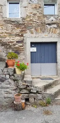 a stone building with two potted plants in front of a door at La petite maison dans le Sidobre in Fontrieu