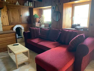 a living room with a red couch and a fireplace at La petite maison dans le Sidobre in Fontrieu
