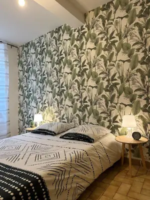 a bedroom with a bed with a floral wallpaper at Charmant Appartement - 2 chambres - Carcassonne Centre in Carcassonne