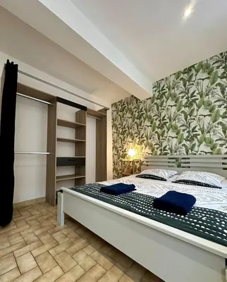 a bedroom with a large bed with blue pillows at Charmant Appartement - 2 chambres - Carcassonne Centre in Carcassonne