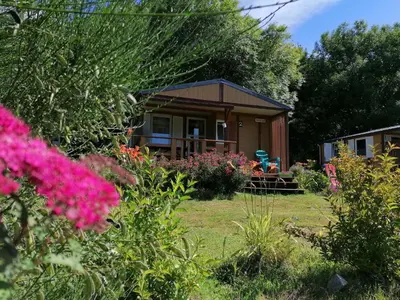 a small cabin in a garden with pink flowers at Hébergement au Lac des Montagnès pour 5 personnes in Mazamet