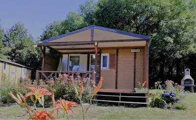 a tiny house with a porch in a garden at Hébergement au Lac des Montagnès pour 5 personnes in Mazamet
