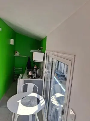 a small kitchen with a table and a green wall at Le studio perché in Carcassonne