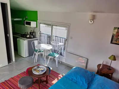 a living room with a couch and a table and a kitchen at Le studio perché in Carcassonne